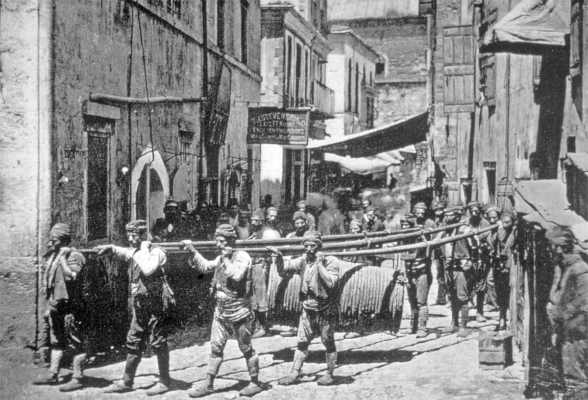 Yağ kapanından aldıkları yağ fıçılarını taşıyan sırık hamalları