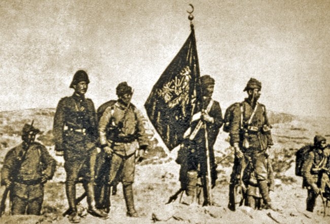 Çanakkale muharebelerinde Arıburnu’na dikilen57. Alay’ın gazi sancağı ve muhafızlarını gösterenbir fotoğraf (AA, I/4 [2. seri, 1949], s. 56)