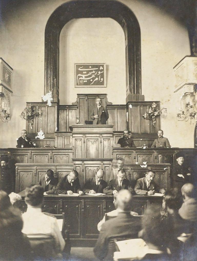 İkinci Türkiye Büyük Millet Meclisi’nin, arkasında “Ve emruhüm şûrâ beynehüm” âyetinin(eş-Şûrâ 42/38) yer aldığı başkanlık kürsüsündeİsmet Paşa konuşma yaparken(İsmail Kara koleksiyonu)